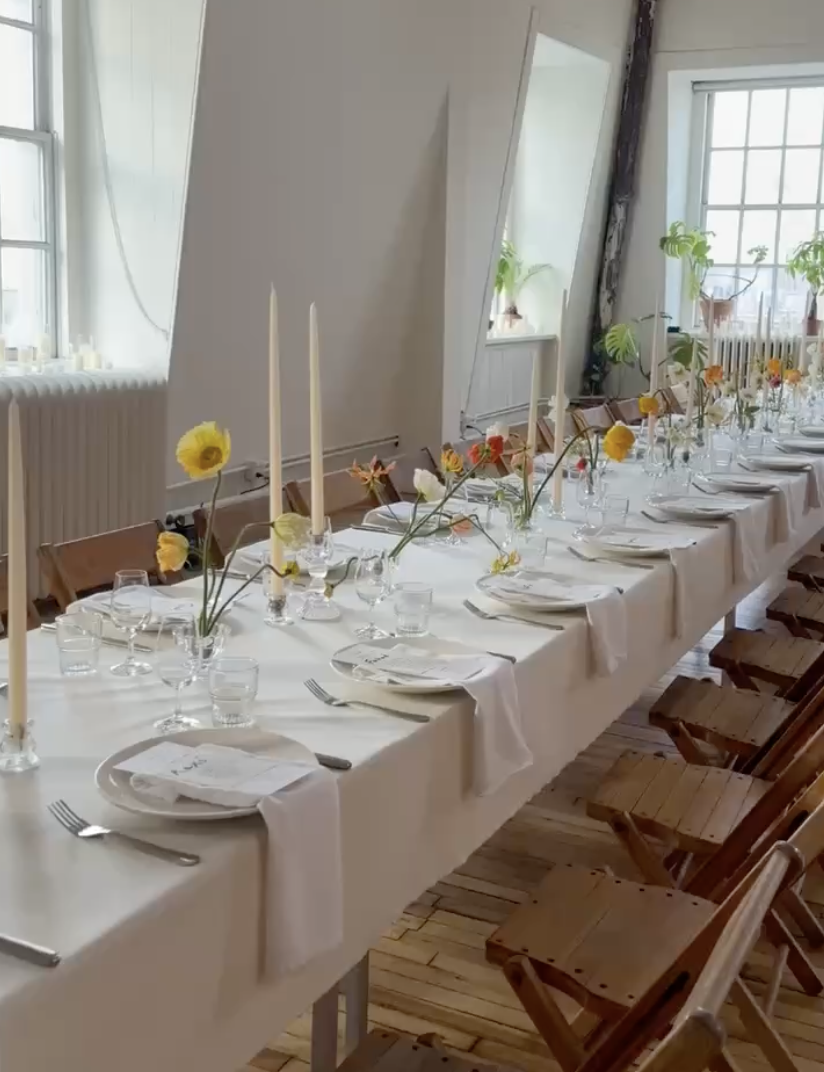 A long dining table set with flowers, candles and glassware